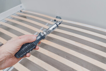 Assembling a frame for a mattress with wooden planks called a rack-and-pinion bed base using a...