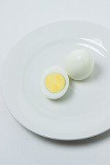 A boiled egg cut in half on a plate. Healthy breakfast. Boiled egg on white background