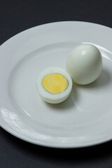 A boiled egg cut in half on a plate. Healthy breakfast. Boiled egg on black background