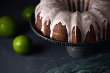 lemon bundt cake on black background accompanied by lemons