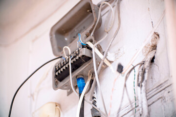 An old junction box with wires on a light wall