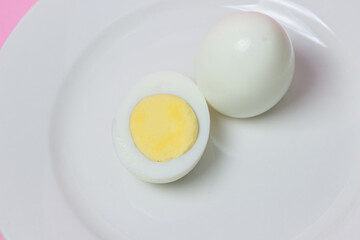 A boiled egg cut in half on a plate. Healthy breakfast. Boiled egg on white background