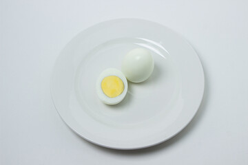 A boiled egg cut in half on a plate. Healthy breakfast. Boiled egg on white background