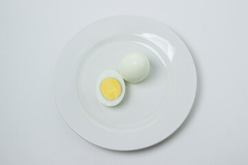 A boiled egg cut in half on a plate. Healthy breakfast. Boiled egg on white background