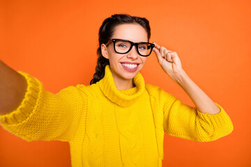 Photo of brown hair optimistic girl do selfie touch spectacles wear yellow sweater isolated on orange color background