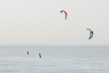 Minimalistic image of two snow kiters on the coast of the Finnish gulf in Saint Petersburg, Russia.