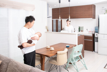 赤ちゃんを抱っこする父親と見守る母親