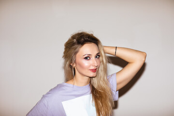 Fototapeta premium Woman in violet shirt with bright make up posing near white wall. Copy space.