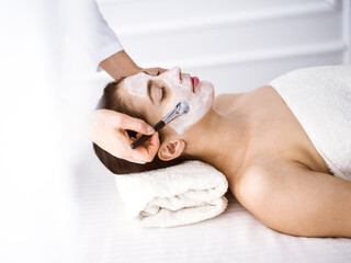 Beautiful brunette woman enjoying applying cosmetic mask comfortable and bissfulle. Relaxing treatment in medicine and spa center concepts