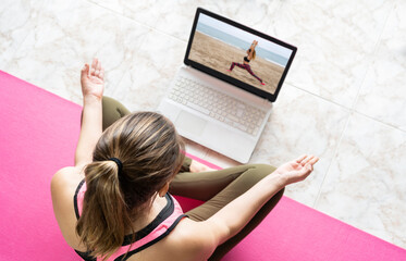 Young woman in lotus position doing yoga watching online class.Virtual yoga couch tutorial , video call education training exercises concept.Healthy lifestyle and stay fit at home.