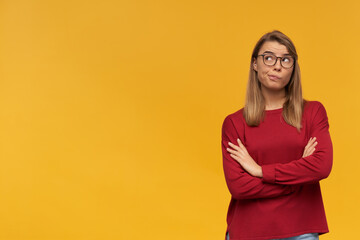 Thoughtful doubting blonde woman.Pursed lips. Looking to the upper left corner standing with hand...