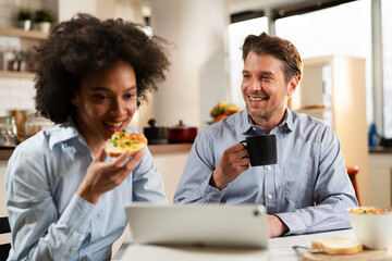 Loving couple drinking coffee and eating sandwich. Happy smiling wife enjoy in the morning with her husband..