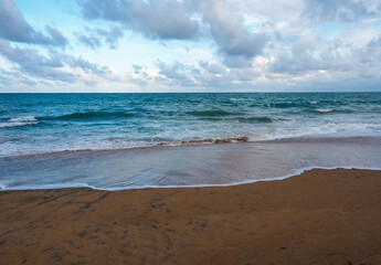 Fototapeta na wymiar the beach in the morning with soft blue wave and sugar sand, cloudy sky