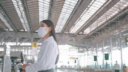 A business woman is wearing protective mask in International airport, travel under Covid-19 pandemic, safety travels, social distancing protocol, New normal travel concept