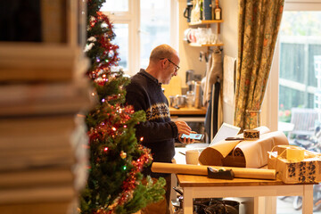 Man wrapping Christmas parcels to send