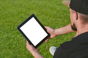 Mockup tablet in the hands of the guy. Against the backdrop of a green lawn.