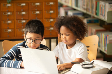 Asian boy and a little cute girl use laptop to study together for learn distance education in the library.