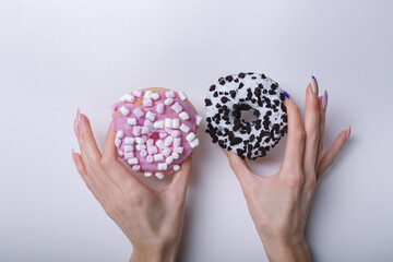 female beautiful hands with fashionable manicure holding donuts