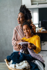 Black ethnicity family doing domestic chores and laundry. Single parent housework.