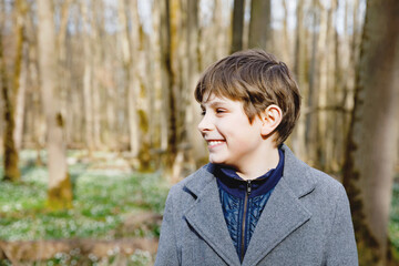 Portrait of preteen school kid boy. Happy smiling child looking at the camera. Boy in spring forest, making family outdoor adventure walk with family.