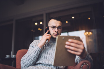 Thoughtful man with clipboard talking on smartphone