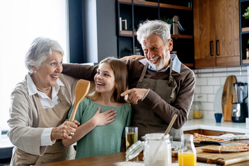 Affectionate senior grandparents in love with child in kitchen