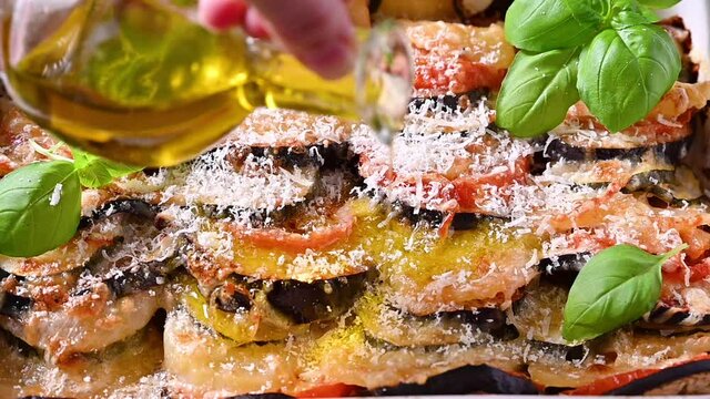 olive oil is poured into lasagna. Traditional italian food. Baked eggplant, tomatoes with sauce, parmesan and basil. Rustic food for a healthy diet. Vegetables for lunch. High quality FullHD footage