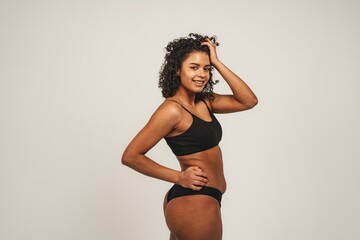 Fototapeta na wymiar Photo of attractive black woman wears black underwear. Isolated over white background. Natural beauty and health