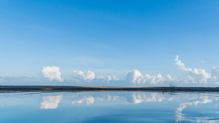 blue sky and white clouds over sand beach reflection on the sea 