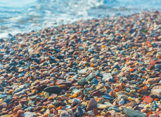 Bright wet pebbles on the coast in the foam of the surf