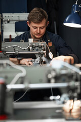 Working process of leather craftsman. Tanner or skinner sews leather on a special sewing machine, close up.worker sewing on the sewing machine