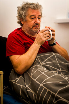 Senior man sitting in bed feeling unwell