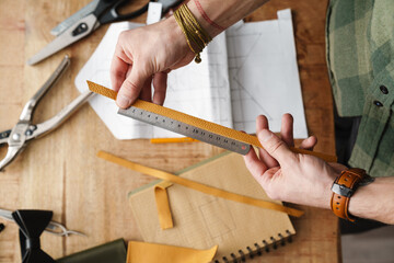 White craftsman working with leather and drawing in workshop