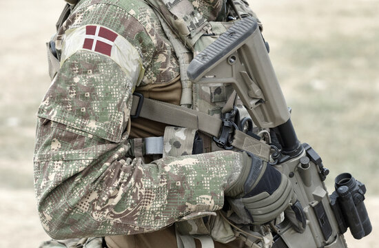 Soldier with assault rifle and flag of Denmark on military uniform. Collage.