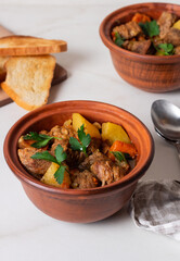 Goulash, beef stew with vegetables and thyme in pots with onion and greens. Irish stew.