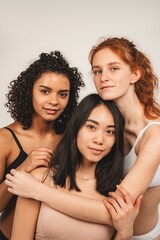 Photo of optimistic cute women, multiracial friends, wear underwear. Feminist females hug each other and show their love. Concept natural beauty and girl power