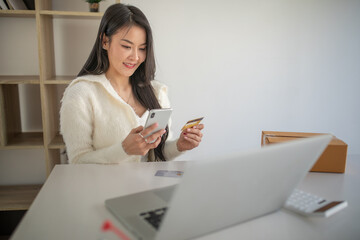 Portrait of young woman using credit card and laptop for Online shopping at home office