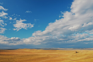Fototapeta na wymiar Fields and open spaces in the steppes of Khakassia against the background of clouds in autumn it is time to harvest cereals