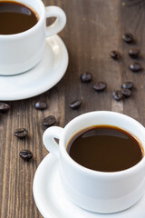 Top view of two white cups with coffee, on wooden table with coffee beans, selective focus, vertical
