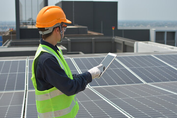 An engineer who works on the inspection and maintenance of equipment at roof-mounted solar power plants of condominium buildings, houses with a tabletop in his hand.