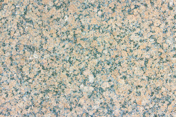 The texture of a hewn granite slab with a colorful pattern. Facing material for walls made of natural stone.