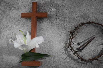 Fototapeta na wymiar Cross with white lilies and crown of thorns on grey background. Christianity Easter concept.