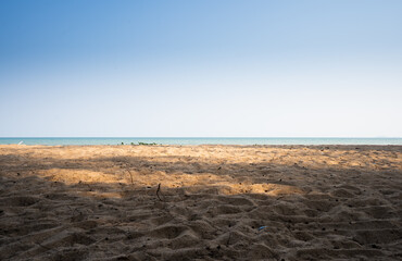 Bright blue sky and sand at the beach, warm sunlight.