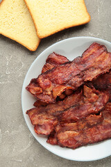 Bacon fried slices in plate on grey background. Top view
