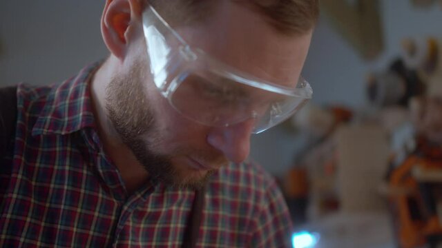 worker at carpenter workspace cutting the edge of wood board using fret saw. Close up. Slow motion Close up face