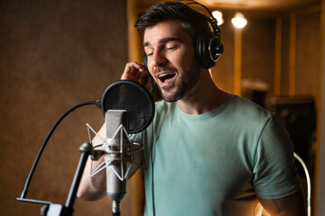 Fototapeta na wymiar Man singing and recording songs in music studio