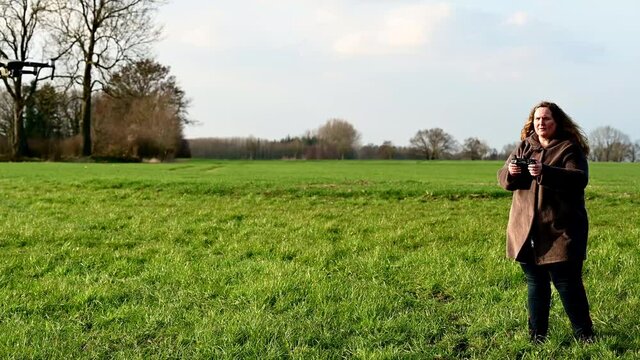 Drohne wird auf einer gr&uuml;nen Wiese von einer Pilotin geflogen
