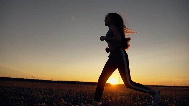 Silhouette of a running girl, healthy lifestyle. Jogging sportswoman at sunset. Silhouette of running athlete man. Girl training at sunset. Outdoor sports training. sports running. beautiful girl.