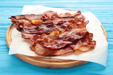 Bacon fried slices on cutting board on blue background. Top view