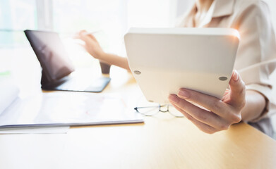Fototapeta premium Business woman using calculator to review balance sheet annual with holding pen and using laptop computer to calculating budget. audit and Check integrity before investment concept.
